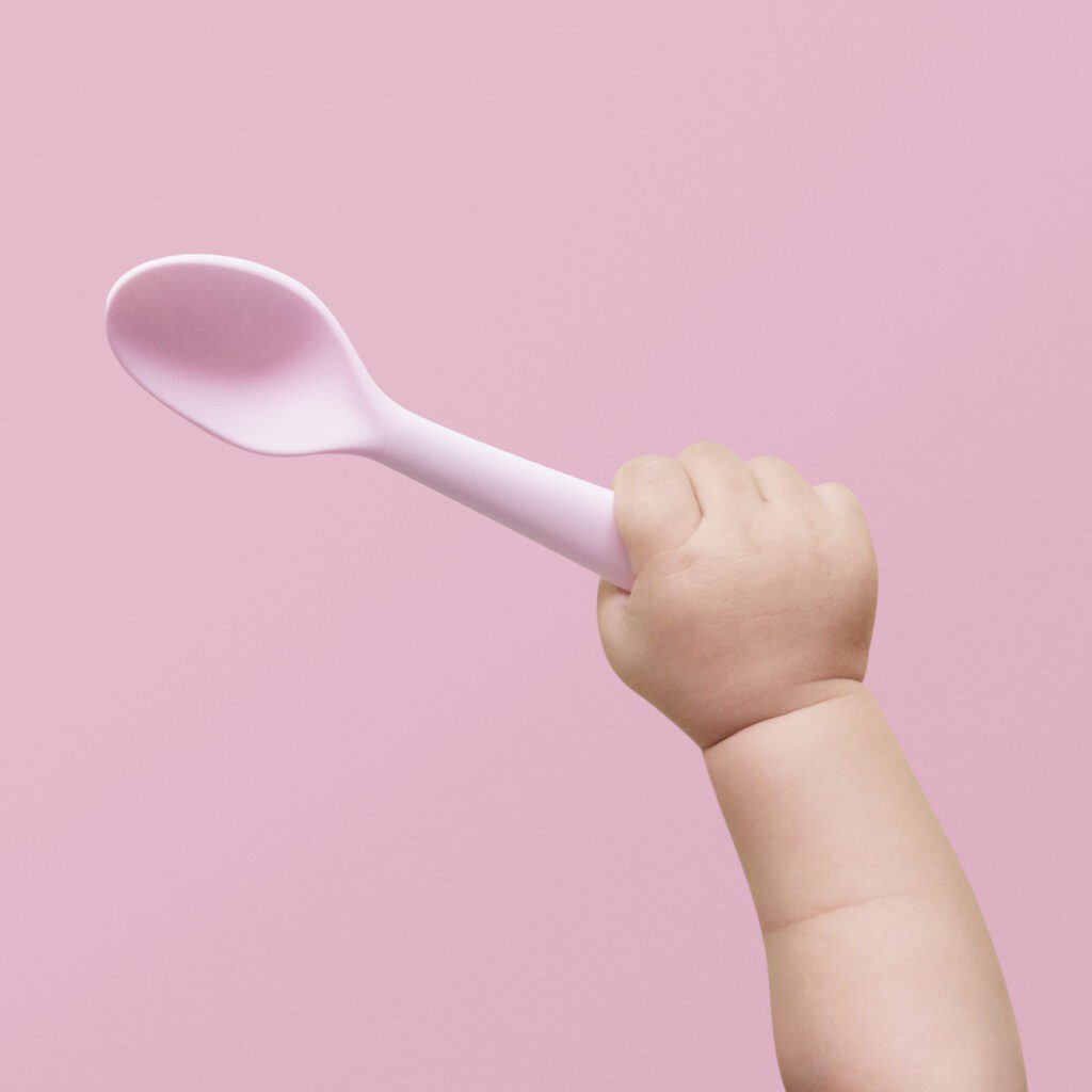 Norwell Pediatrics - Baby hand holding pink plastic spoon